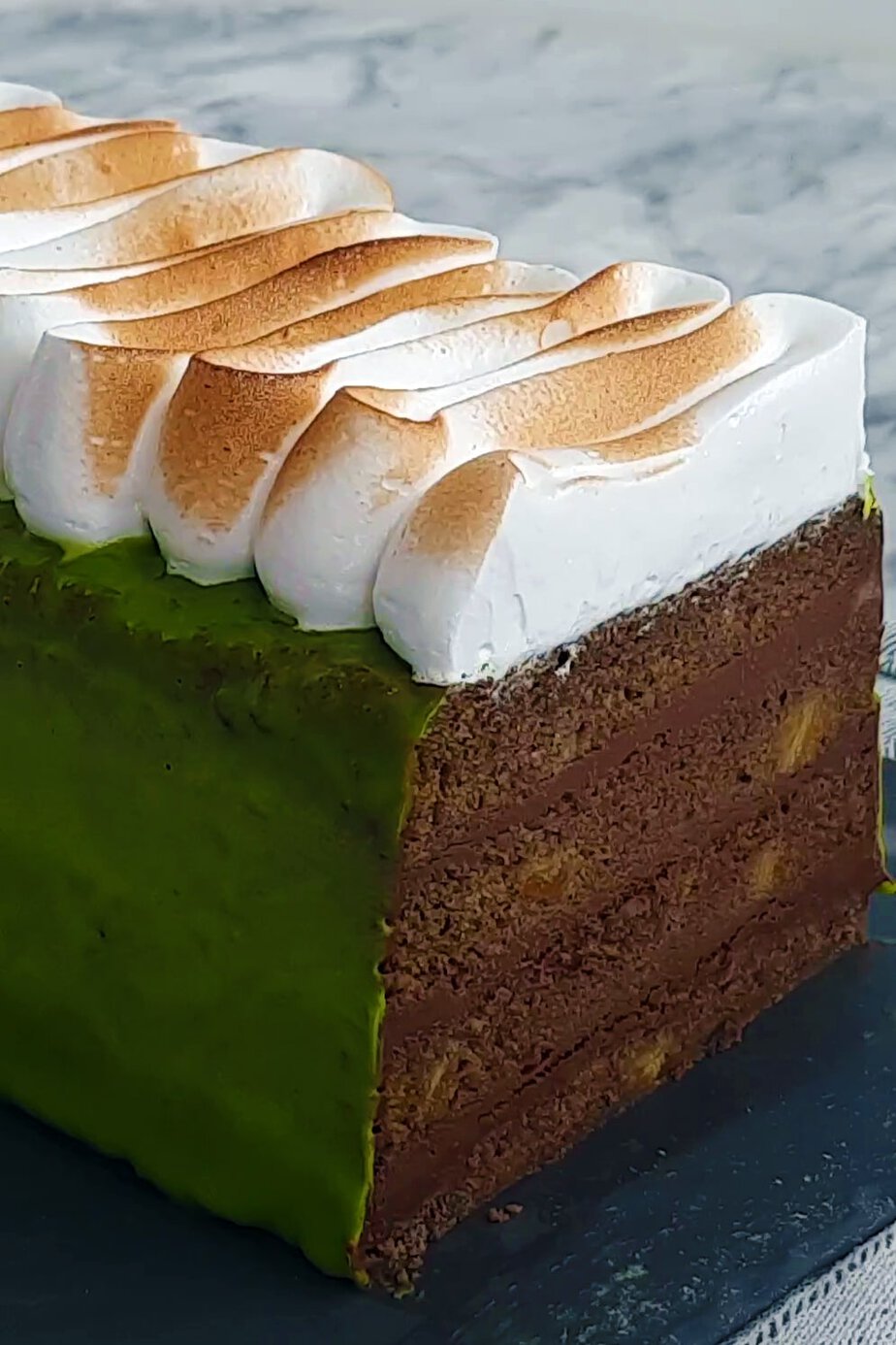 Gâteau banane matcha coupé : glaçage vert, strates de ganache au chocolat noir et meringue brûlée