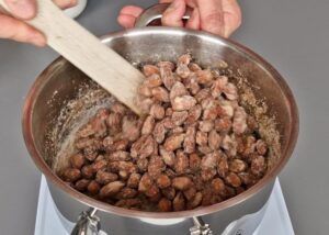 Amandes caramélisées en 3 ingrédients (sans gluten) - Continue à cuire les amandes sur feu moyen en remuant sans arrêt. L’eau va s’évaporer progressivement et le sucre va cristalliser sur les amandes. Ce processus prend environ 10-15 minutes.