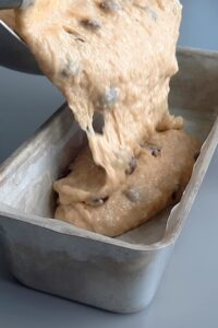 Banana bread chocolat sans gluten - Ajoute les pépites de chocolat à la pâte, puis transvase dans un moule à cake et fais cuire dans un four préchauffé à 180°C pendant environ 40 à 45 minutes.