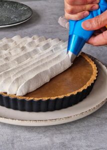 Banoffee pie vegan à la ganache café (sans gluten) - Termine la tarte en pochant la crème fouettée à la vanille sur la ganache au café.