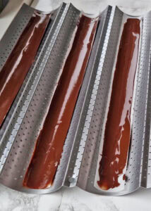 Bûche sans gluten chocolat et châtaigne - Pose les bandes sur une surface légèrement courbée ou plate, puis laisse le chocolat durcir au réfrigérateur ou à température ambiante dans une pièce froide.