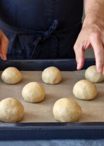 Buns sans gluten au zeste d’orange - Dispose les pâtons façonnés sur une plaque de cuisson recouverte de papier cuisson. Couvre avec un torchon humide ou du film alimentaire. Laisse pousser dans un endroit chaud 60-90 minutes ou jusqu’à ce qu’ils aient doublé de volume.