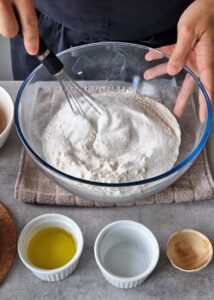 Buns sans gluten au zeste d’orange - Dans un grand saladier, mélange le mélange de farines sans gluten, la levure chimique, le sucre et le sel. Mélange bien.