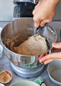 Buns sans gluten au zeste d’orange - Mélange la pâte à la main jusqu’à ce qu’elle soit bien homogène et forme une boule. De même, pétris 4-5 minutes au robot pâtissier muni du crochet. Racle de temps en temps les parois et le fond du bol avec une spatule en caoutchouc pour éviter toute farine non incorporée.