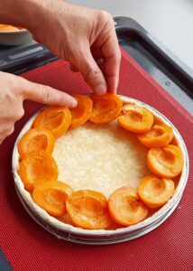 Clafoutis sans gluten à l’abricot et au romarin - Dispose soigneusement les abricots sur la pâte, puis verse délicatement la crème infusée sur les abricots.