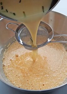 Clafoutis sans gluten à l’abricot et au romarin - Fouette dans un saladier la farine sans gluten, le sucre, les œufs, le lait infusé et la crème, la poudre/extrait de vanille et le sel jusqu’à obtenir une préparation lisse. Passe au tamis pour retirer les grumeaux et les morceaux de feuilles de romarin.
