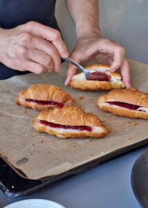 Croissant aux amandes sans gluten à la confiture de fruits rouges - Étale une cuillerée de confiture dans les croissants humidifiés. Garnis les croissants avec deux cuillères à soupe de crème d’amande par-dessus la confiture.