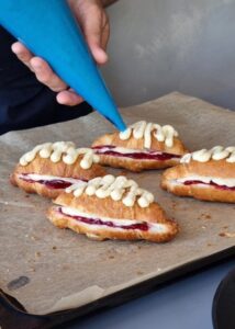 Croissant aux amandes sans gluten à la confiture de fruits rouges - Poche deux cuillères à soupe de crème d’amande sur le dessus des croissants garnis, puis parsème d’amandes effilées sur le dessus. Tu peux aussi presser le croissant garni sur les amandes effilées au lieu de les parsemer. Ainsi, la crème d’amande s’étale sur le dessus pour retenir davantage d’amandes.