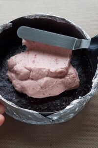 Entremets sans gluten vegan - Étale uniformément la crème pâtissière à la framboise sur la compotée de myrtilles congelée, puis ajoute uniformément les biscuits graham écrasés par-dessus pour former une couche.