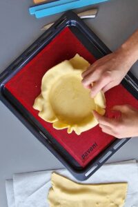 Flan sans gluten aux agrumes - Presse bien la pâte sur les côtés, puis pique le fond avec une fourchette.