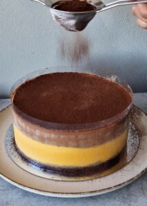 Gâteau à la courge sans gluten à 3 couches - Avant de découper et de servir, saupoudre le dessus de cacao en poudre avant de retirer la feuille d’acétate. Tu peux aussi ajouter du chocolat noir râpé ou des graines de citrouille grillées pour plus de texture.