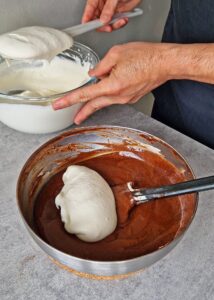 Gâteau au chocolat vegan sans gluten à la mangue - Fouette la crème entière jusqu’à ce qu’elle soit légèrement ferme. Incorpore la moitié de la crème fouettée à la préparation mangue-chocolat chaude jusqu’à homogénéité. Incorpore le reste de la crème fouettée jusqu’à ce que la mousse soit lisse et bien mélangée. Place la mousse sur la casserole remplie d’eau chaude pour la garder au chaud.