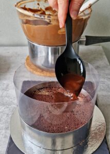 Gâteau au chocolat vegan sans gluten à la mangue - Découpe le biscuit selon la taille du cercle à gâteau. Place la première couche de biscuit au chocolat au fond du cercle à gâteau. Assure-toi qu’elle soit bien ajustée et centrée uniformément, puis imbibe-la de sirop mangue-chocolat.