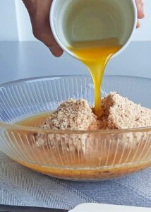 Gâteau mangue passion (sans gluten) - Mélange les miettes et le beurre fondu sans lactose dans un bol jusqu’à obtenir un mélange homogène.