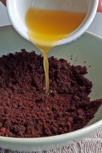 Gâteau mousse au chocolat vegan à 3 couches (sans gluten) - Réduis les biscuits au chocolat en miettes, puis mélange les miettes avec le beurre vegan fondu.