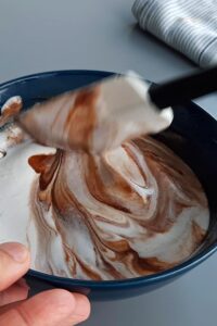 Gâteau mousse au chocolat vegan à 3 couches (sans gluten) - Fais fondre au bain-marie le chocolat noir vegan avec la crème entière. Incorpore délicatement la crème montée au chocolat fondu encore chaud jusqu’à obtenir une texture lisse.