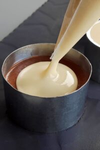 Gâteau mousse au chocolat vegan à 3 couches (sans gluten) - Poche la mousse au chocolat blanc sur la mousse au chocolat au lait ferme.