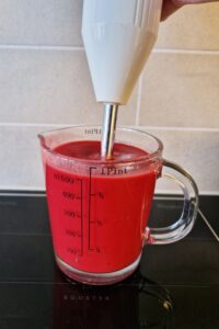 Glaçage miroir vegan (sans gluten) - Verse le liquide chaud sur le chocolat blanc et le colorant alimentaire, puis mixe au mixeur plongeant jusqu’à obtenir une texture lisse.