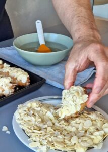 Mini croissant aux amandes vegan sans gluten - Poche environ une cuillère à soupe de crème d’amande sur le dessus des mini croissants garnis puis presse la crème d’amande pochée sur les amandes effilées.