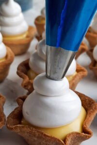 Mini tarte au citron meringuée sans gluten - Poche la meringue sur les fonds de tartelettes garnis. Brûle la meringue avec un chalumeau de cuisine. Saute cette étape si tu n’as pas de chalumeau de cuisine.