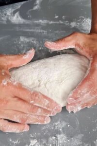 Pain sans gluten en cocotte, deux méthodes - Dégaze et façonne la pâte en forme oblongue sur une surface farinée avec de la farine sans gluten.