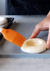Pavlova vegan (sans gluten) - Badigeonne les disques de meringue de beurre de cacao fondu sur le dessus et le dessous. Cela scellera la surface de la meringue et l’empêchera de ramollir.