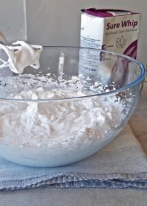 Pavlova vegan (sans gluten) - Fouette la crème sans produits laitiers dans un bol jusqu’à ce qu’elle soit légère et aérienne. Ajoute la vanille pour une note de saveur supplémentaire.