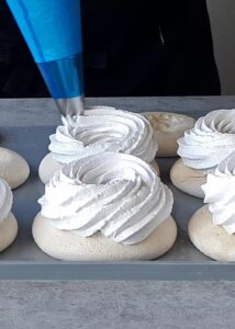 Pavlova vegan (sans gluten) - Poche la crème fouettée avec une douille étoilée tout autour des côtés de la meringue, en laissant le milieu creux.