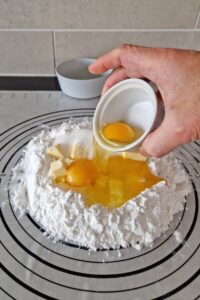 Quiche aux champignons sans gluten sans fromage - Travaille les cubes de beurre froid, le sel, le sucre et les œufs sur une surface froide avec tes doigts jusqu’à obtenir une texture de miettes.