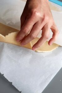 Sablés sans gluten fourrés à la ganache - Étale la pâte froide entre deux feuilles de papier cuisson sur une épaisseur d’environ 3-4 mm.