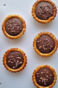 Tarte au chocolat sans gluten peu sucrée - Saupoudre d’éclats de cacao sur le dessus.