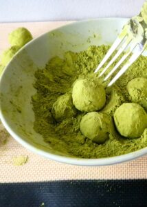 Truffes au matcha sans sucre ajouté (sans gluten) - Roule les boules de ganache dans un bol de poudre de matcha.