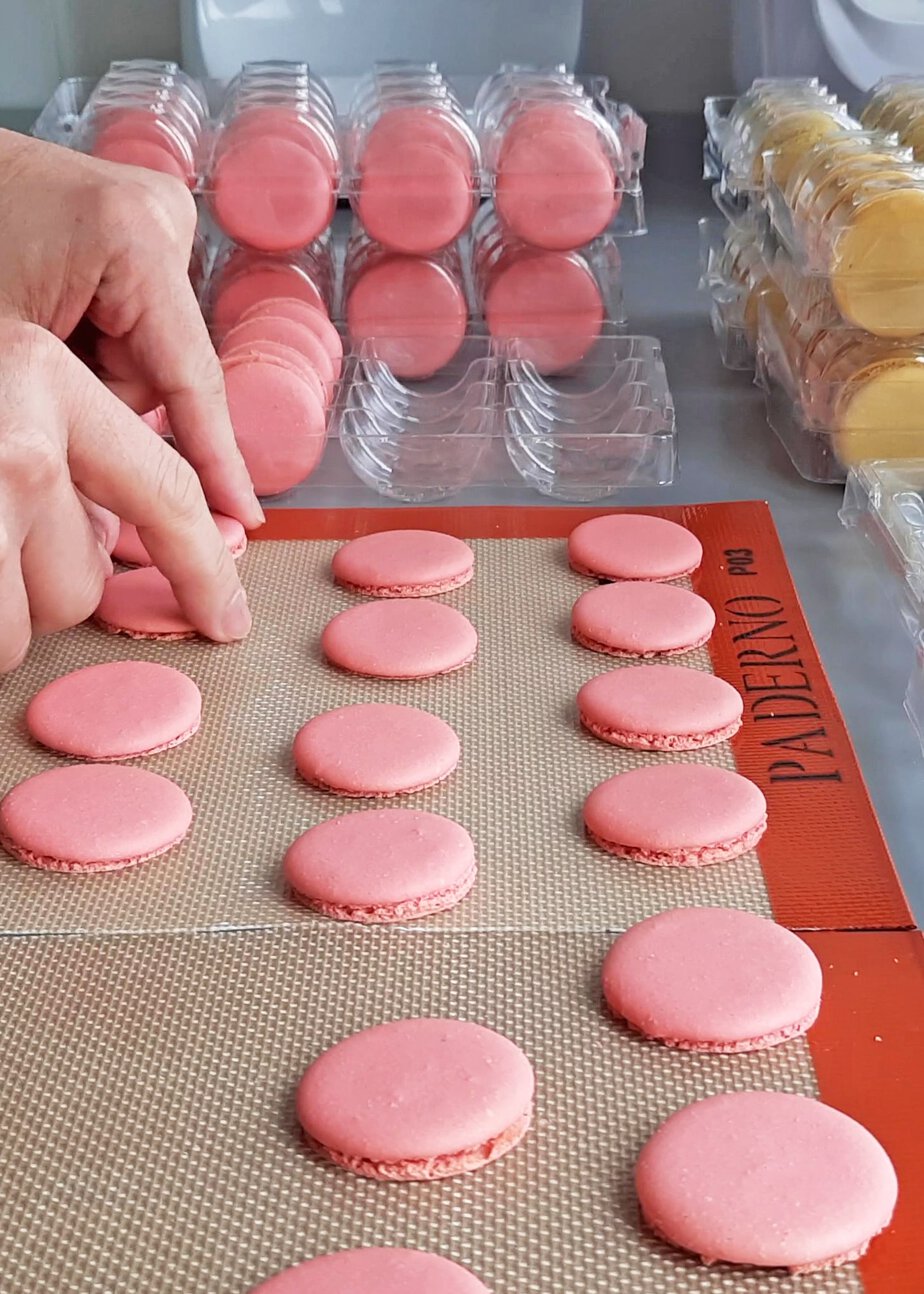 Coques de macarons roses triées à la main sur un tapis en silicone avant garnissage