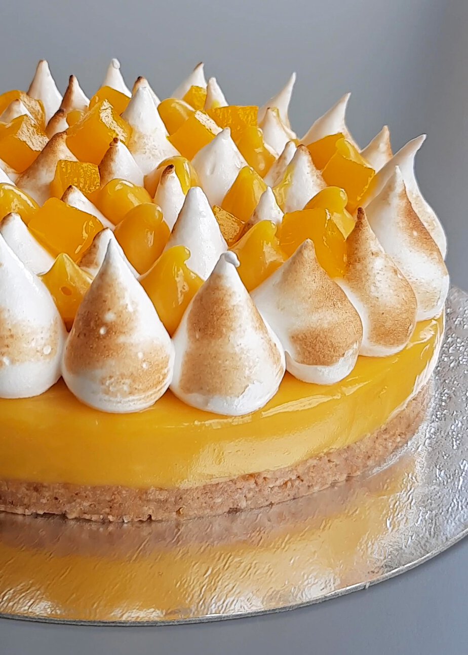 Gâteau mangue passion sans gluten couvert de pointes de meringue vegan brûlées au chalumeau et de dés de mangue