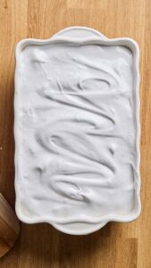 Meringue crue étalée sur la crème dans le plat