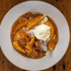Cobbler aux pêches servi à l'assiette avec une boule de glace vanille