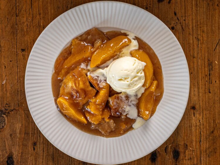 Cobbler aux pêches servi à l'assiette avec une boule de glace vanille