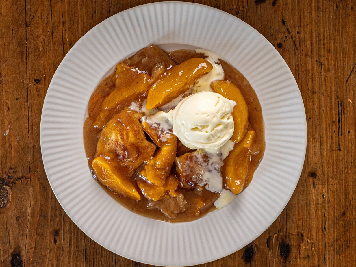 Cobbler aux pêches servi à l'assiette avec une boule de glace vanille