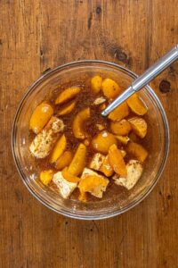 Pêches au sirop, beurre, sucre, vanille et épices réunis dans un saladier