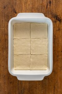 Carrés de pâte disposés au fond d'un plat graissé