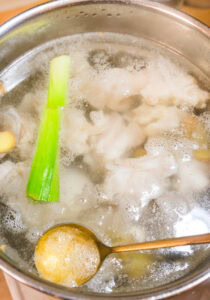 Gyusuji nikomi - Rincer la casserole, puis ajouter l'eau, les tendons, le gingembre et la partie verte du poireau. Porter à ébullition, écumer et cuire 5 minutes.