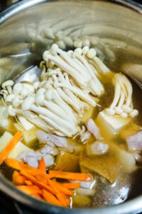 Tōnyū nabe - Ajouter le poulet, le tofu, l'aburaage, la carotte et les champignons.