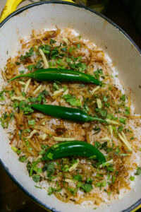 Biryani au poulet - Parsemer le reste des oignons frits, les piments verts fendus, le gingembre en julienne et le reste des herbes.