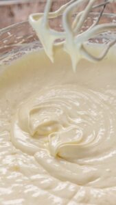 Garniture au fromage frais lisse et épaisse sous les fouets du batteur