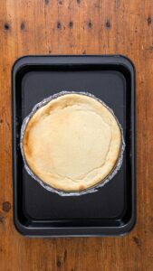 Cheesecake cuit dans son moule posé dans le plat du bain-marie, les bords dorés