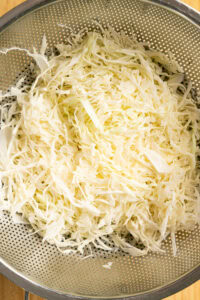 Coleslaw - Saupoudrer le sucre et le sel sur le chou, puis bien mélanger.