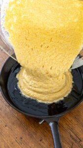 Pâte à cornbread versée dans la graisse chaude de la poêle en fonte