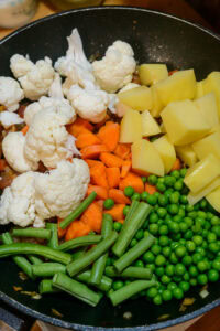 Curry de légumes - Ajouter la carotte, le chou-fleur, les petits pois, la pomme de terre, les haricots et le sel.