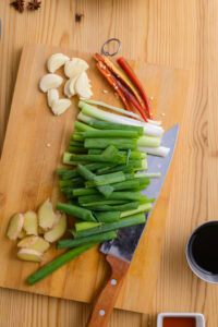 Gua bao - Fendre les piments en deux, écraser l'ail, couper les oignons verts en tronçons.
