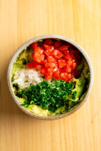 Guacamole - Incorporer le reste de l'oignon, la coriandre et la tomate si elle est utilisée.